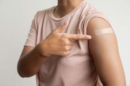 Asian woman shows plaster on her shoulder after being vaccinated against virus vaccination campaign concept.の写真素材