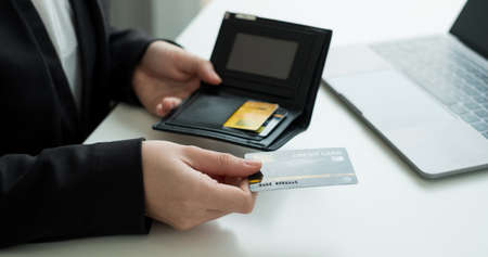 The businesswomen's hand is holding a credit card and using a laptop for online shopping and...