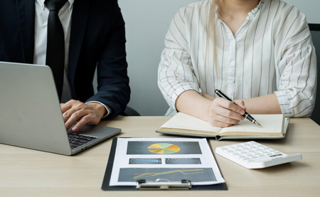 Two business leaders talk about charts, financial graphs showing results are analyzing and...