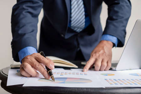 work from home, The hand of the businessman who works in finance at home and calculates financial graphs showing the results of his investments, planning the steps of his business growth.の写真素材