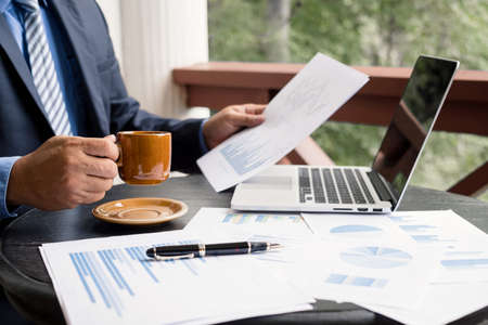 work from home, The hand of the businessman who works in finance at home and calculates financial graphs showing the results of his investments, planning the steps of his business growth.の写真素材