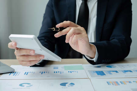 The hand of businessman sit at their desks and calculate financial graphs showing results about...