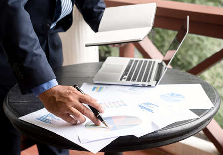 work from home, The hand of the businessman who works in finance at home and calculates financial graphs showing the results of his investments, planning the steps of his business growth.の写真素材