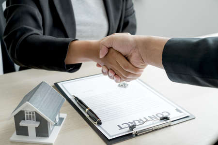 Business and brokers real estate agents shake hand after completing negotiations to buy houses insurance and sign contracts. Home insurance concept.の写真素材