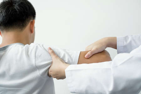Female physiotherapists provide physical assistance to male patients with shoulder injuries massage...