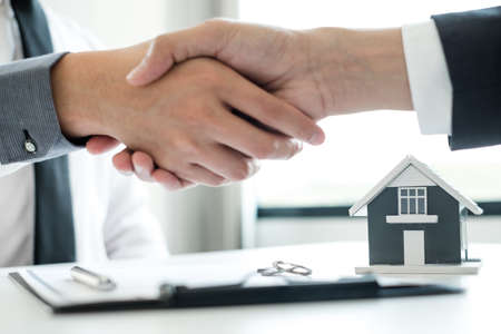 Businessmen and brokers' real estate agents shake hands after completing negotiations to buy houses insurance and sign contracts. Home insurance concept.の写真素材