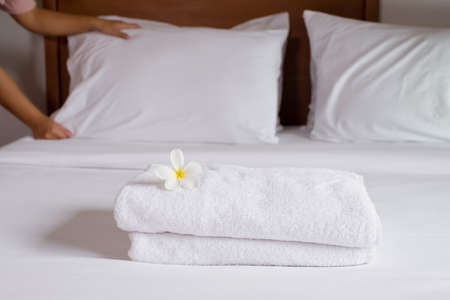 A hotel maid stacked towels on the bed and placed flowers on the towels in a hotel room.の写真素材