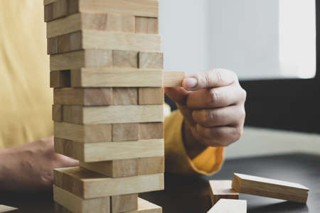 Hands of businesswomen playing wooden block game. Concept Risk of management and strategy plans for...