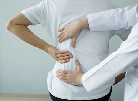 Female physiotherapists provide physical assistance to male patients with back injuries back massages for relaxation and muscle recovery in the rehabilitation center.の写真素材