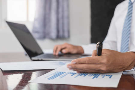 The businessman hand sits at their desks and calculates financial graphs showing the results of...