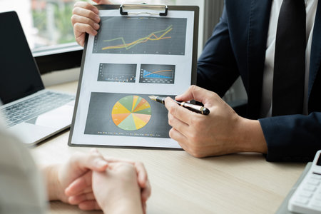 Two business leaders talk about charts, financial graphs showing results are analyzing and...