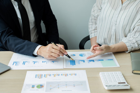 Two business leaders talk about charts, financial graphs showing results are analyzing and...