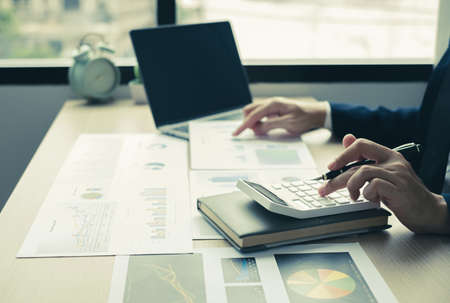 The hand of businessman sit at their desks and calculate financial graphs showing results about...