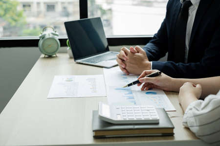 Two business leaders talk about charts, financial graphs showing results are analyzing and...