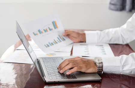 The businessman hand sits at their desks and calculates financial graphs showing the results of...