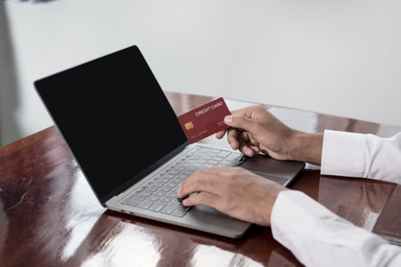 The businessman's hand is holding a credit card and using a laptop for online shopping and internet payment.の写真素材