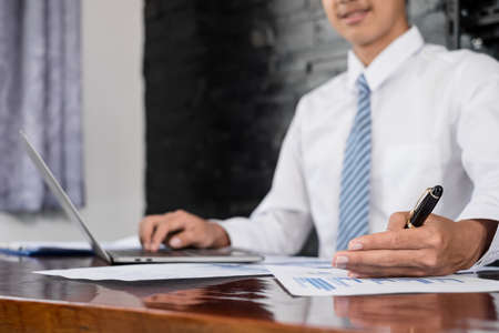 The businessman hand sits at their desks and calculates financial graphs showing the results of...
