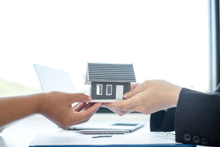 Real estate agent broker hand over the home to the new owner after completing the signing according to agreement renting a house and buy house insurance Home insurance concept.の写真素材