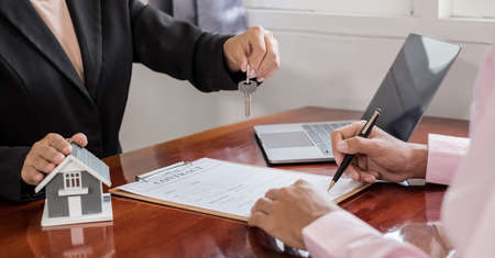 Real estate agent broker hand over the house key to the new owner after completing the signing...
