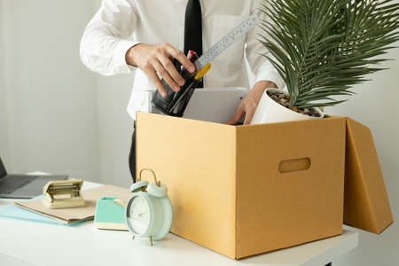 A male office worker is unhappy with being fired from a company packing things into cardboard boxes....