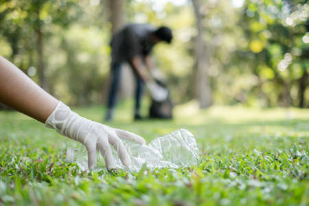 garbage collection, volunteer team pick up plastic bottles, put garbage in black garbage bags to clean up at parks, avoid pollution, be friendly to the environment and ecosystem.の写真素材