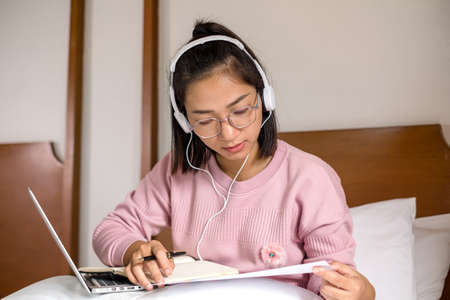 work from home, a young Asian woman who works in finance at home calculates financial graphs showing the results of his investments, planning the steps of his business growth.の写真素材