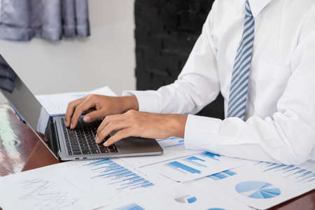 The businessman hand sits at their desks and calculates financial graphs showing the results of...