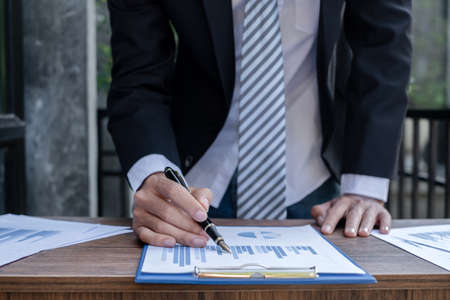 Young businessman financial market analyst sits at their desks and calculate financial graphs showing the results of their investments planning the process of successful business growth.の写真素材