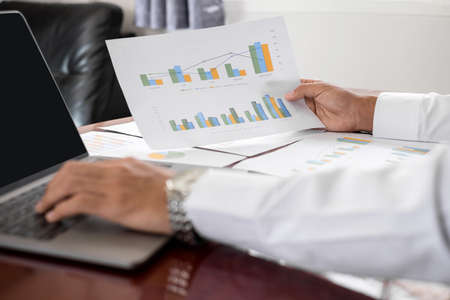The businessman hand sits at their desks and calculates financial graphs showing the results of...