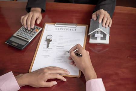 A real estate agent with rental homes and home insurance for clients to sign contracts under a formal home lease agreement. Home rental and insurance concept.の写真素材