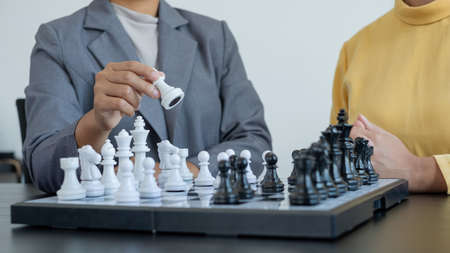 The hands of businesswomen two people moving chess in chess competitions demonstrate leadership, followers, and strategic plans, business success building processes, and teamwork.の写真素材