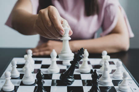 Hand of businesswoman moving, chess in competition shows leadership, followers, and business success strategies.の写真素材