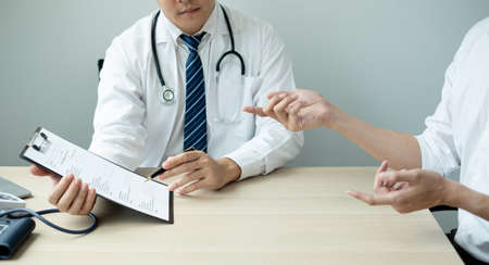 The male doctor sat and checked the patient's history and listened to the patient to clarify the symptoms. Concepts of treatment and good health.の写真素材
