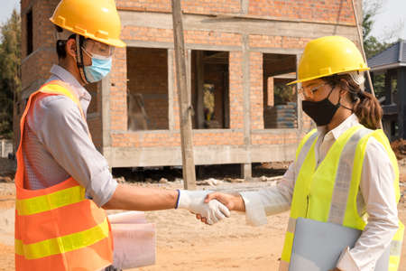 Shake hand, the team of male and female engineers or architects is exploring and inspecting the outdoor construction site work.の写真素材