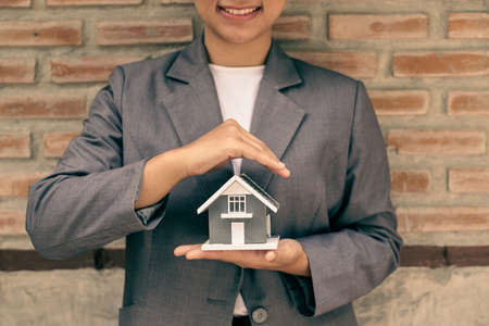 The house is covered by the hands of a real estate agent to protect the house for customers, homebuyers, insurance, ready give to with new owner. Home insurance sales concept.の写真素材