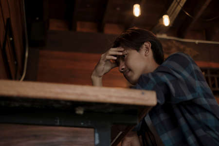 A young Asian man sits at the bar counter in a restaurant to relax.の写真素材