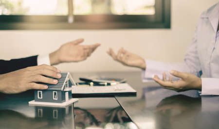 A real estate agent with the House model is talking to clients about buying home insurance. Home insurance concept.の写真素材