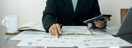 The businesswoman hand sits at their desks and calculates financial graphs showing the results of...