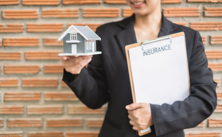 Home insurance concept and real estate. Businesswoman holding a house model working in investment about renting a house, buying a house, and home insurance.の写真素材