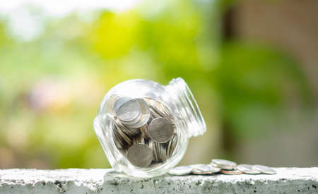 Retirement savings concept. bottle glass and coins with green nature background and copy space.