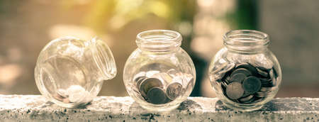 Retirement savings concept. bottle glass and coins with green nature background and copy space.の写真素材