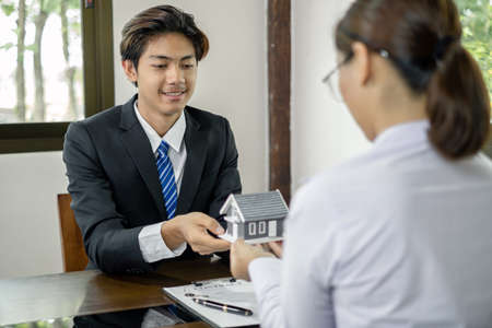 The real estate agent gives the house to a new owner's client after completing the signing of the lease and formally completing home insurance. Rental and insurance concepts.の写真素材