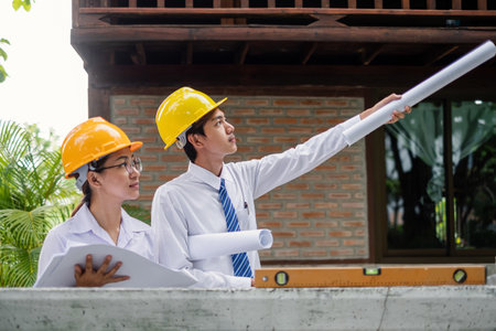 Team of male and female engineers and architects, working team, meeting, discussing construction, and inspecting the outdoor construction site work.の写真素材
