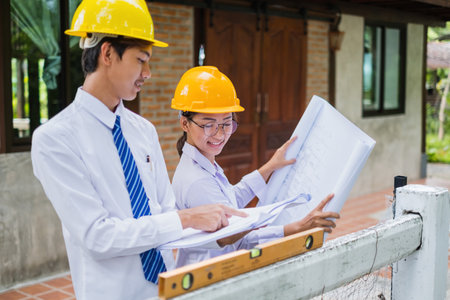 Team of male and female engineers and architects, working team, meeting, discussing construction, and inspecting the outdoor construction site work.の写真素材