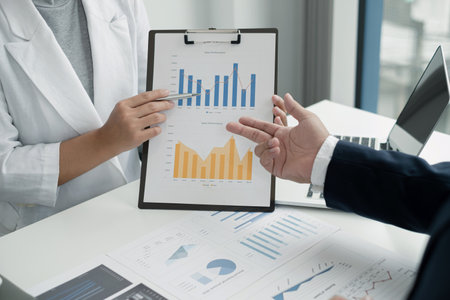 Two business leaders talk about charts, financial graphs showing results are analyzing and...