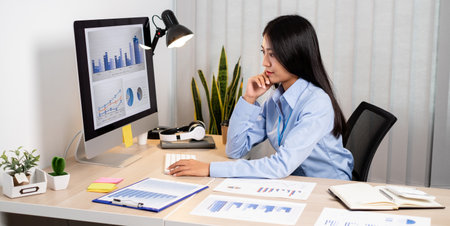 Asian woman working on a laptop with a cheerful and happy smile while working at the office.の写真素材