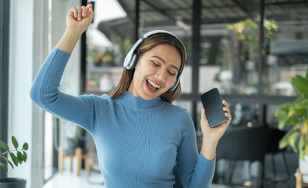 Happy Asian girl wearing headphones listening to music enjoy on smartphone digital. relaxation concepts.の写真素材