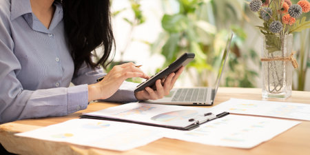 Asian businesswoman sit at their desks and calculate financial graphs showing results about their investments, plan a successful business growth process.の写真素材