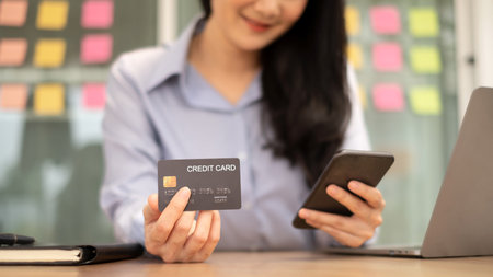 Asian girl shopping online holding credit and using smartphone enter their card number in the mobile phone app to purchase and payment in internet store.の写真素材