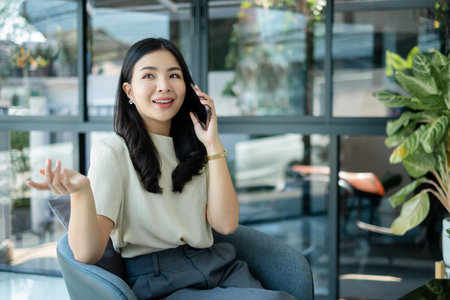 Young Asian woman talking on the mobile phone working on smartphone In modern office.の写真素材